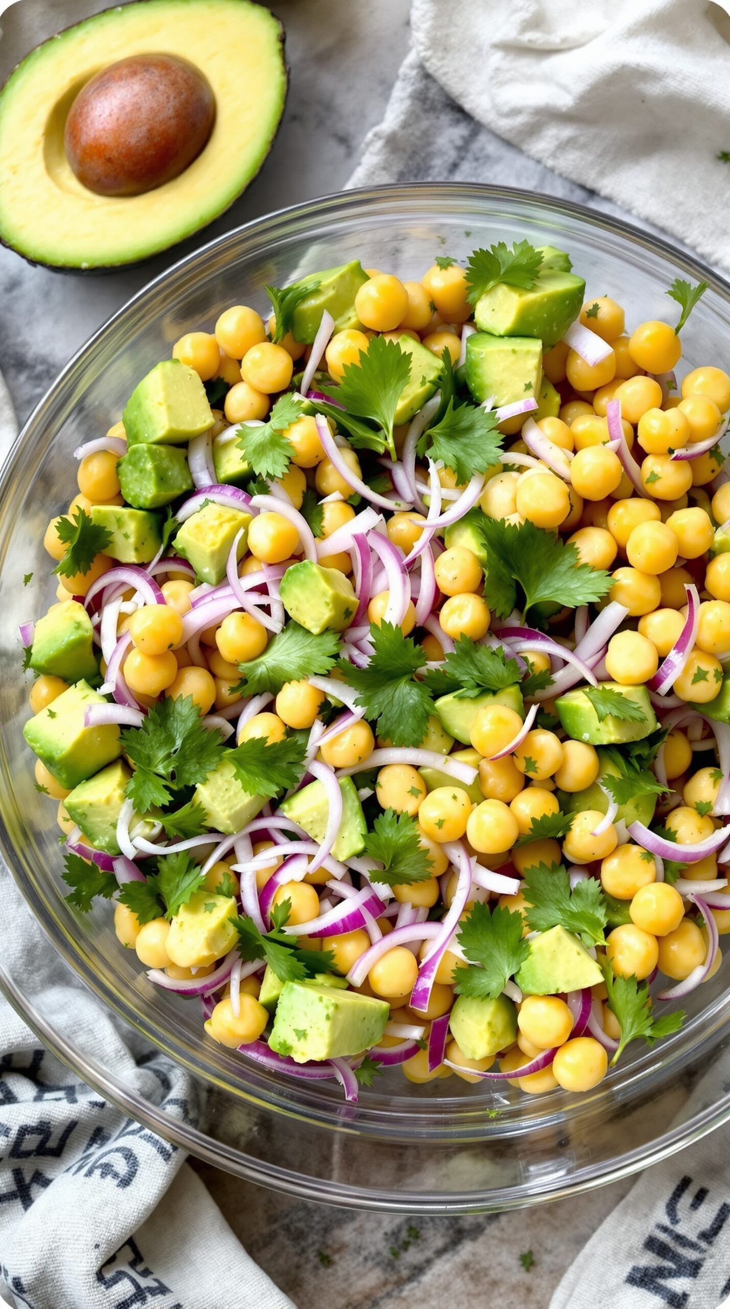 A bowl of chickpea and avocado salad with cilantro and red onion.