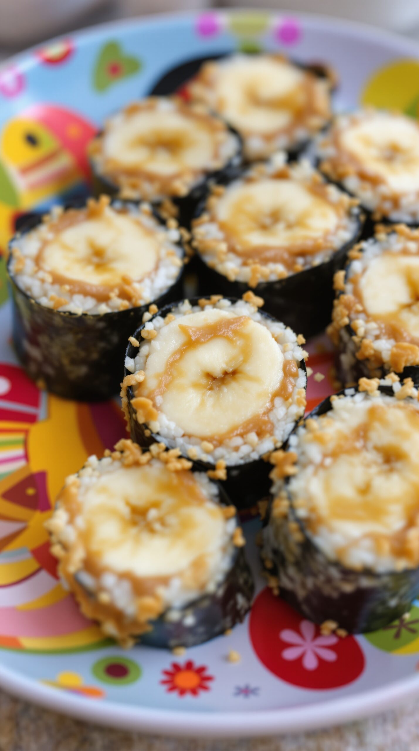 Peanut butter banana sushi rolls displayed on a colorful plate